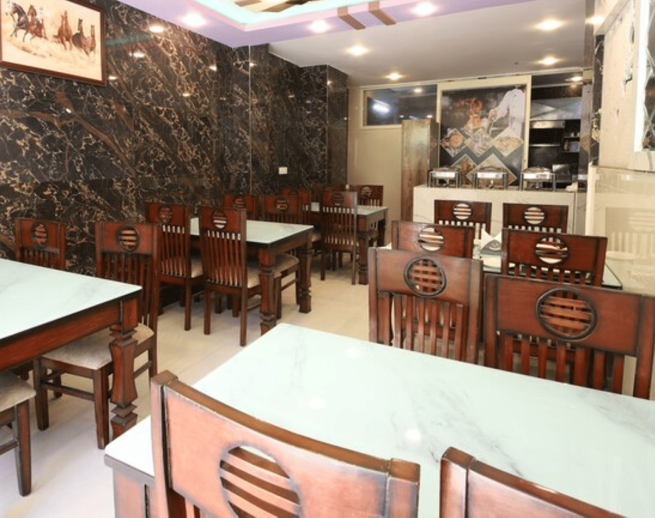 A side angle view of a dining area with neatly arranged chairs around square dining tables | Perfectstayz Value Hills, Rishikesh