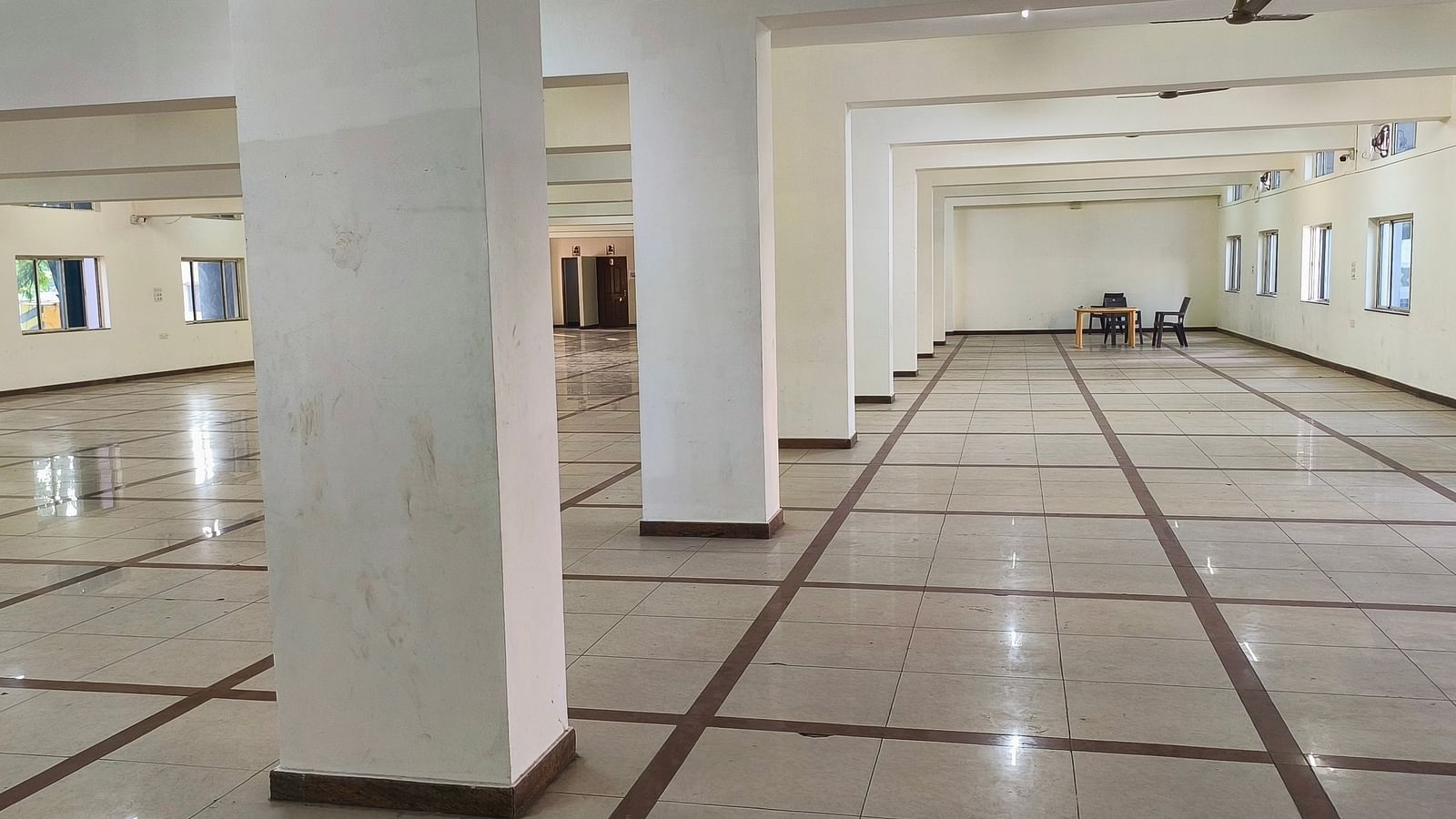A bright, empty banquet hall within BNGV Grandeur Hotel and Banquets, showcasing the hall's clean and open design.