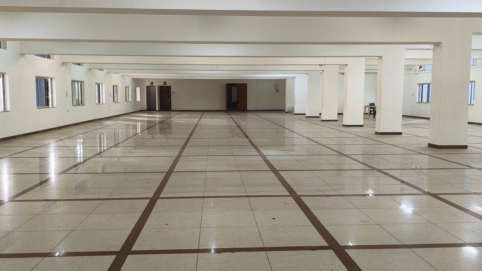 A vast, empty banquet hall in BNGV Grandeur Hotel and Banquets with a polished marble floor, ready for a large event.