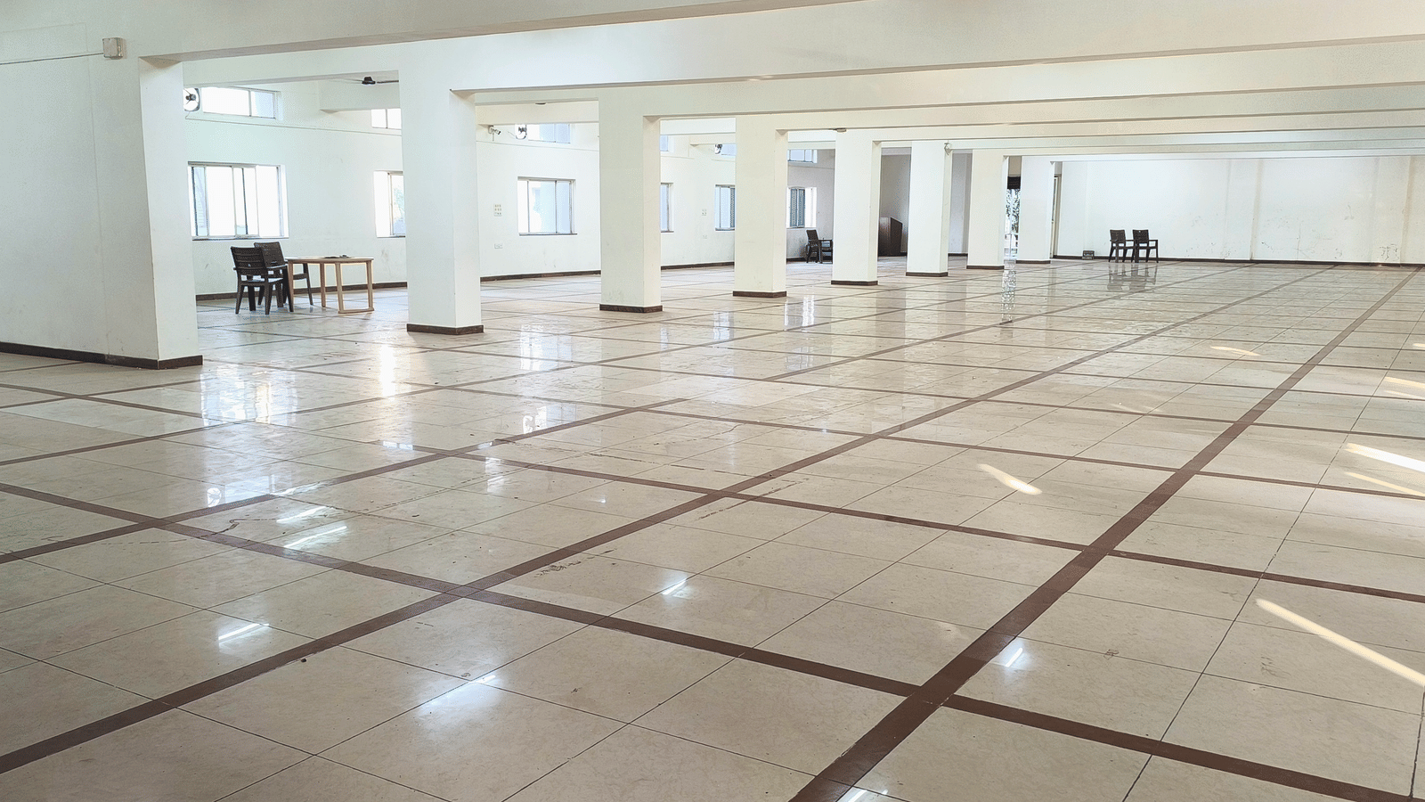 A long view of a spacious, empty banquet hall at BNGV Grandeur Hotel and Banquets, showing the extensive floor space and architectural details.