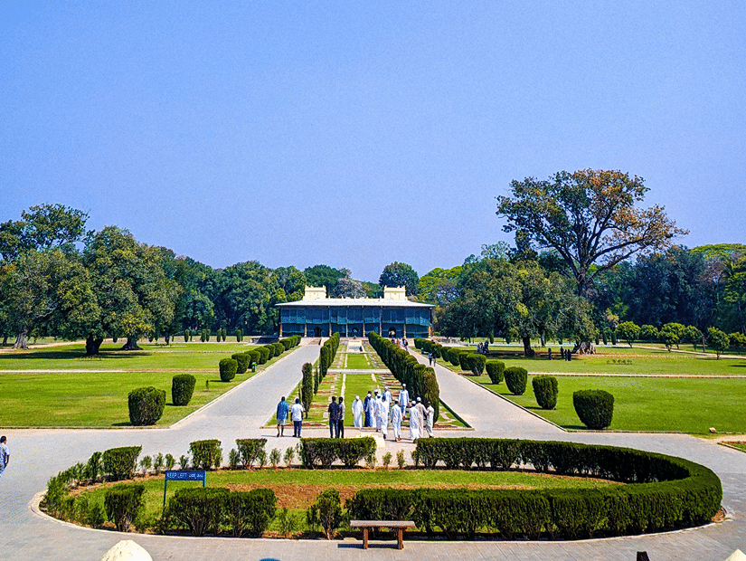 A wide angle view of the Tipu Sultan Summer Palace with its front gardens under a clear blue sky.