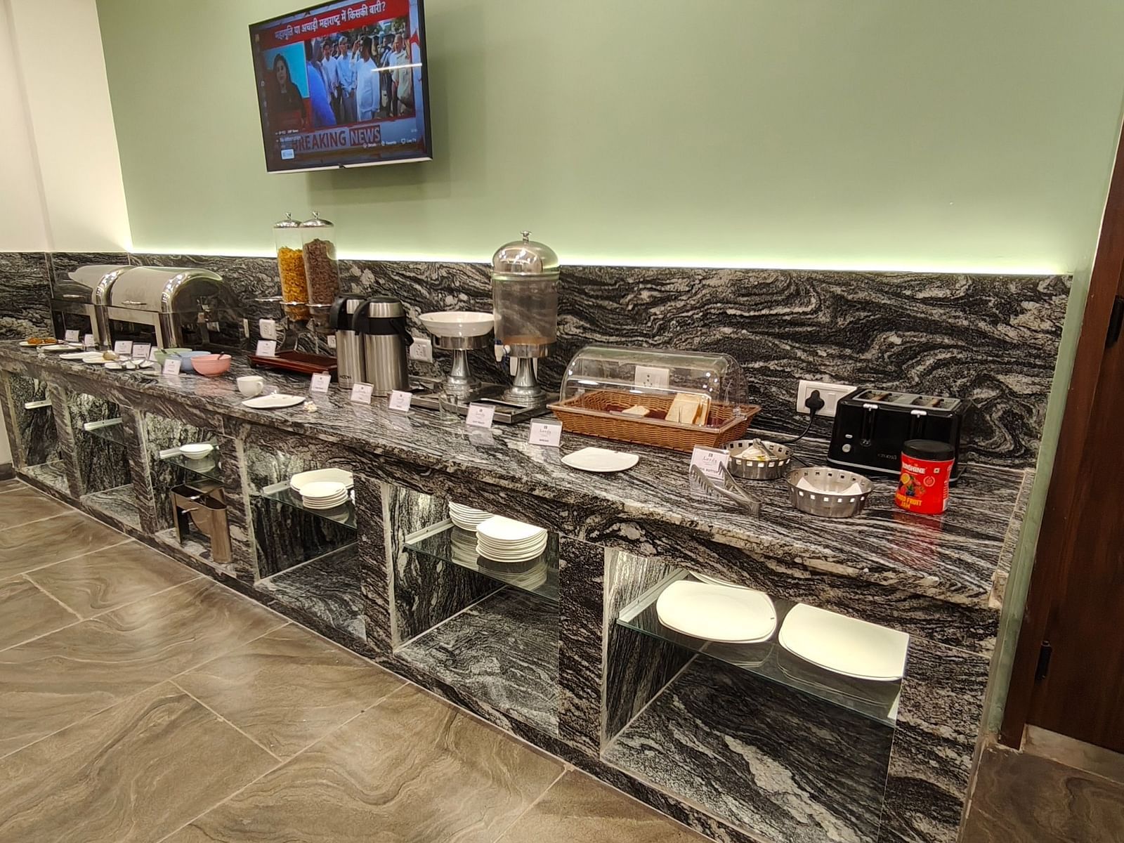 Buffet counter setup with various serving dishes and a mounted TV