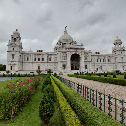 A view of Kolkata Victoria Park from afar with the grass area on either side of the walkway leading to the Victoria memorial in the background.