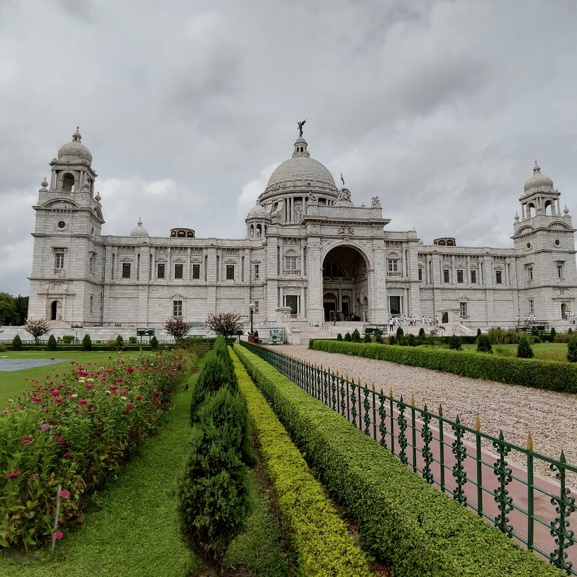 A view of Kolkata Victoria Park from afar with the grass area on either side of the walkway leading to the Victoria memorial in the background.
