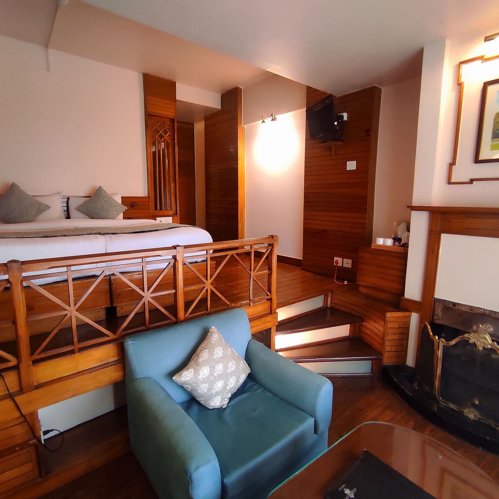 The Deluxe Room in Cedar Inn, Darjeeling features a separate living area, a fireplace and a double bed.