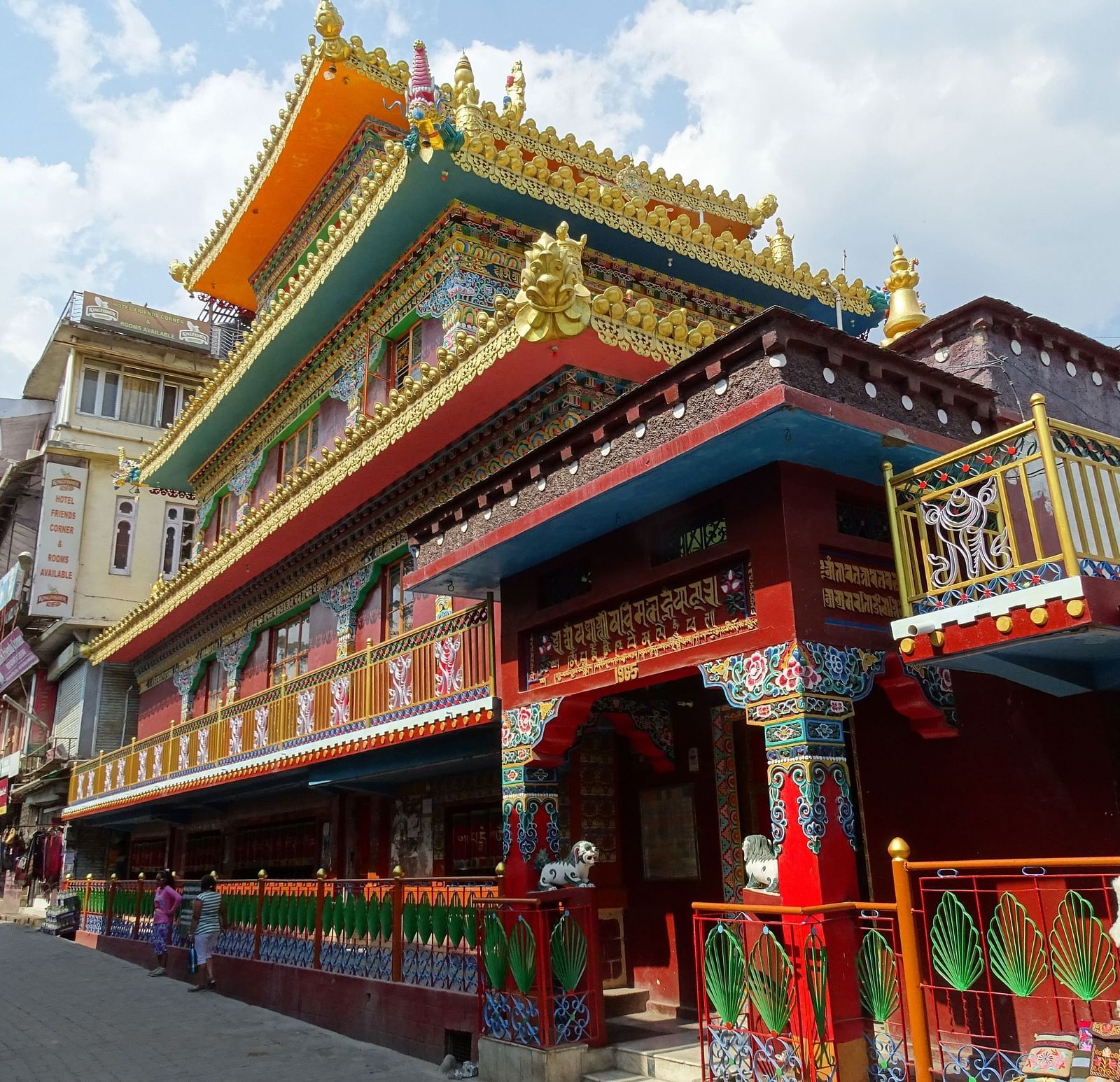 An image of a monastery near a road where people are seen walking