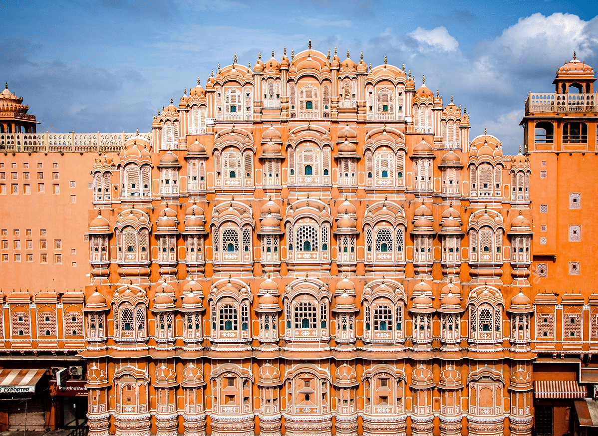 Hawa Mahal, Jaipur, with its distinctive pink facade and numerous small windows, under a blue sky.