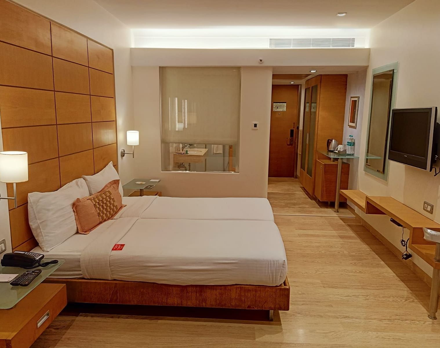Image of twin beds in the executive twin room at our hotel featuring a flat screen television, bed side table, mirror, and other furniture. | Mirage Hotel