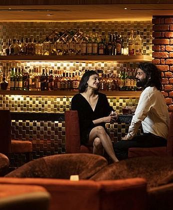 A man and a woman sitting at a well-lit Dovka Bar - Nirvana Luxury Hotel, Ludhiana.