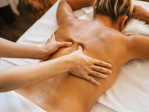 Swedish Massage performed on the back a person lying face down on a white sheet