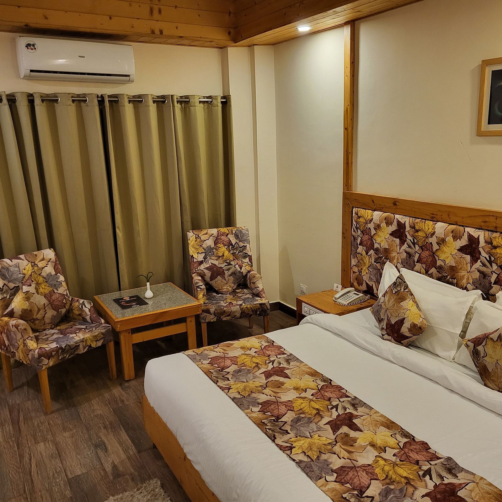 Side angle of the bedroom, featuring comfortable seating, elegant curtains, and wooden flooring at Dagshai Manor Kasauli - Inde Hotels.
