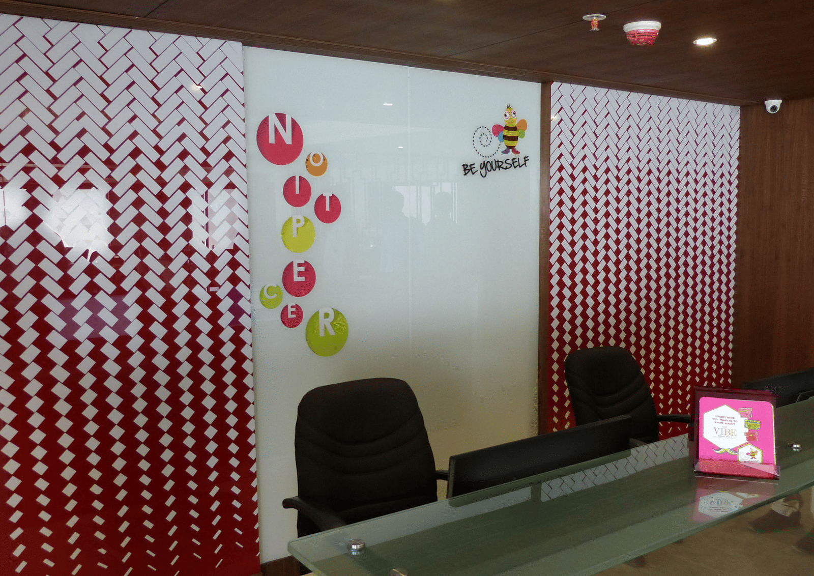 The reception area of Zibe Coimbatore by GRT Hotels featuring a desk with two chairs neatly arranged.