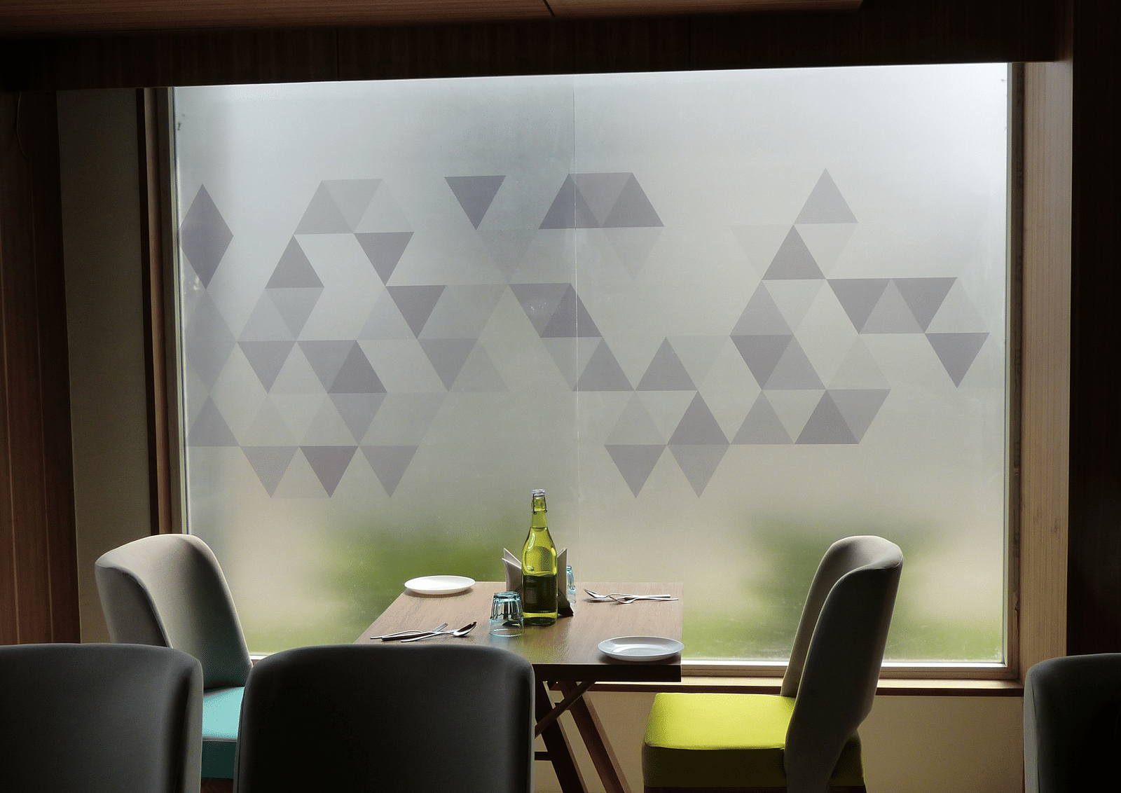 The table is neatly set with cutlery, and two seats are placed on each side, next to the window