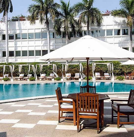 Swimming pool with seating area besides it at The Claridges New Delhi