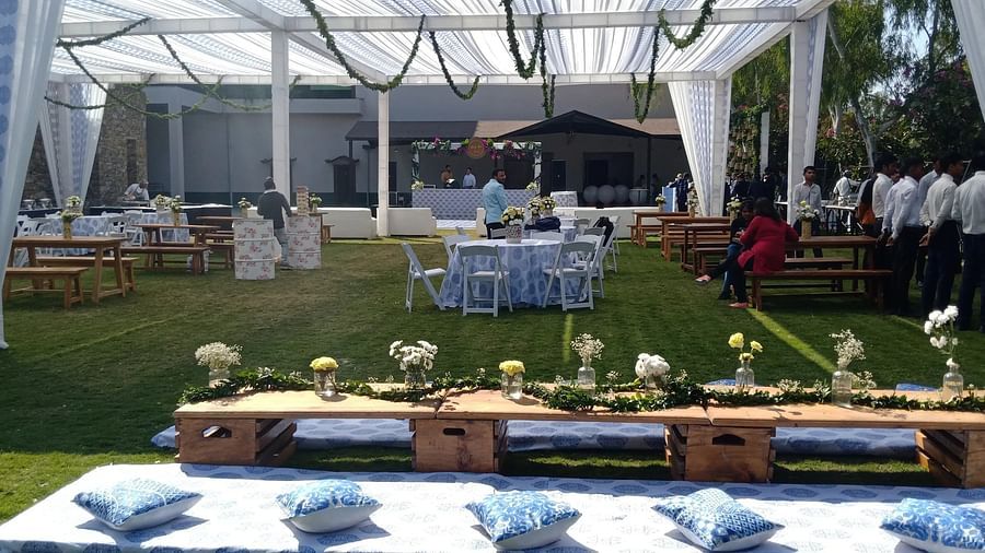 Outdoor event setup with a tent, tables, chairs, and decorations on a lawn. - Bamboo Saa, Udaipur