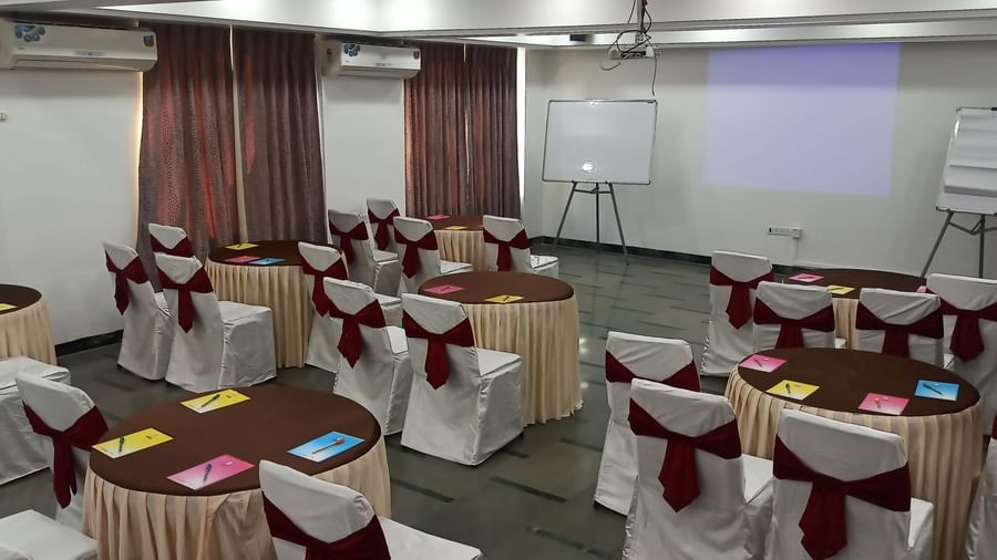 Training room setup with cluster seating arrangement, notepads, and a projection screen at Mayur Retreat.