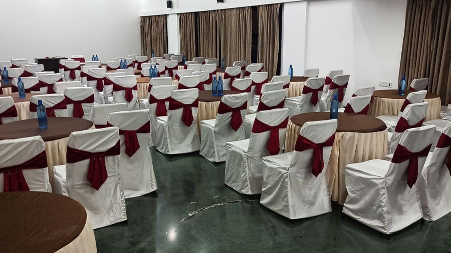 Cluster seating arrangement with white covers and maroon chair sashes, suitable for formal dining or events at Mayur Retreat.