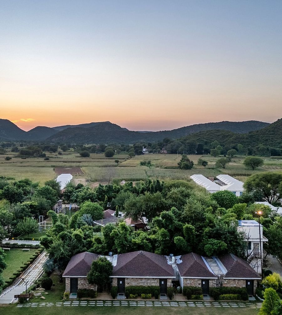 Aerial view of Valley by Grassfield, surrounded by lush greenery with mountains in the background.
