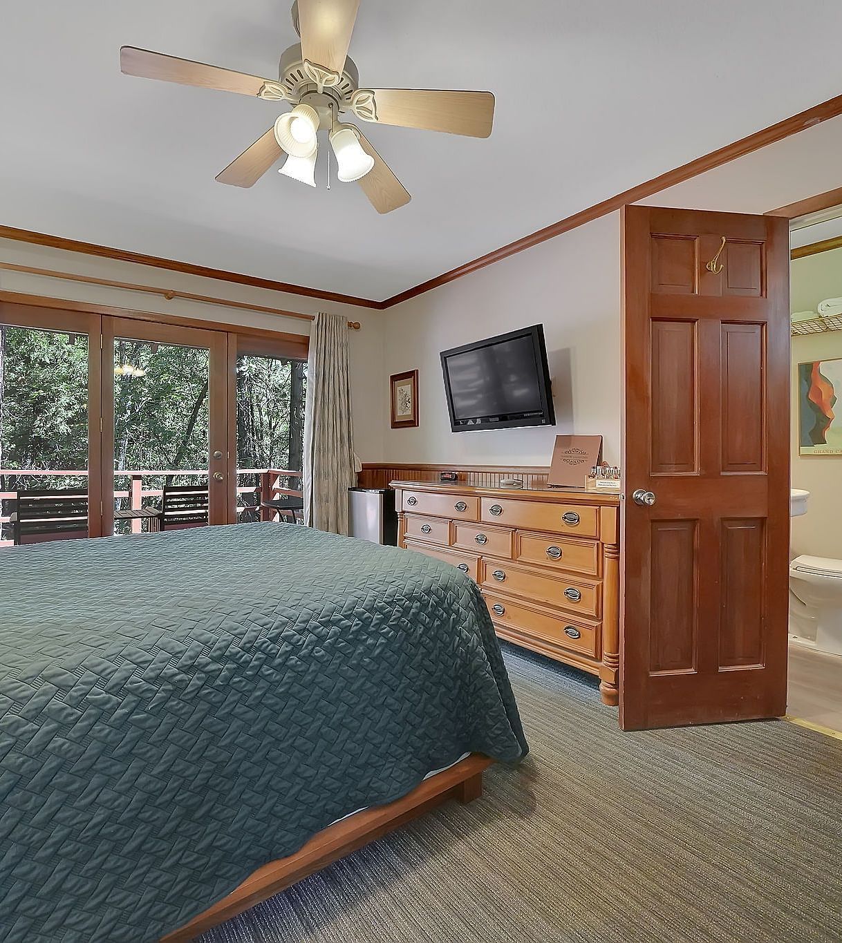 A view of a room at Narrow Gauge Inn with a double bed and sliding doors opening to a balcony.