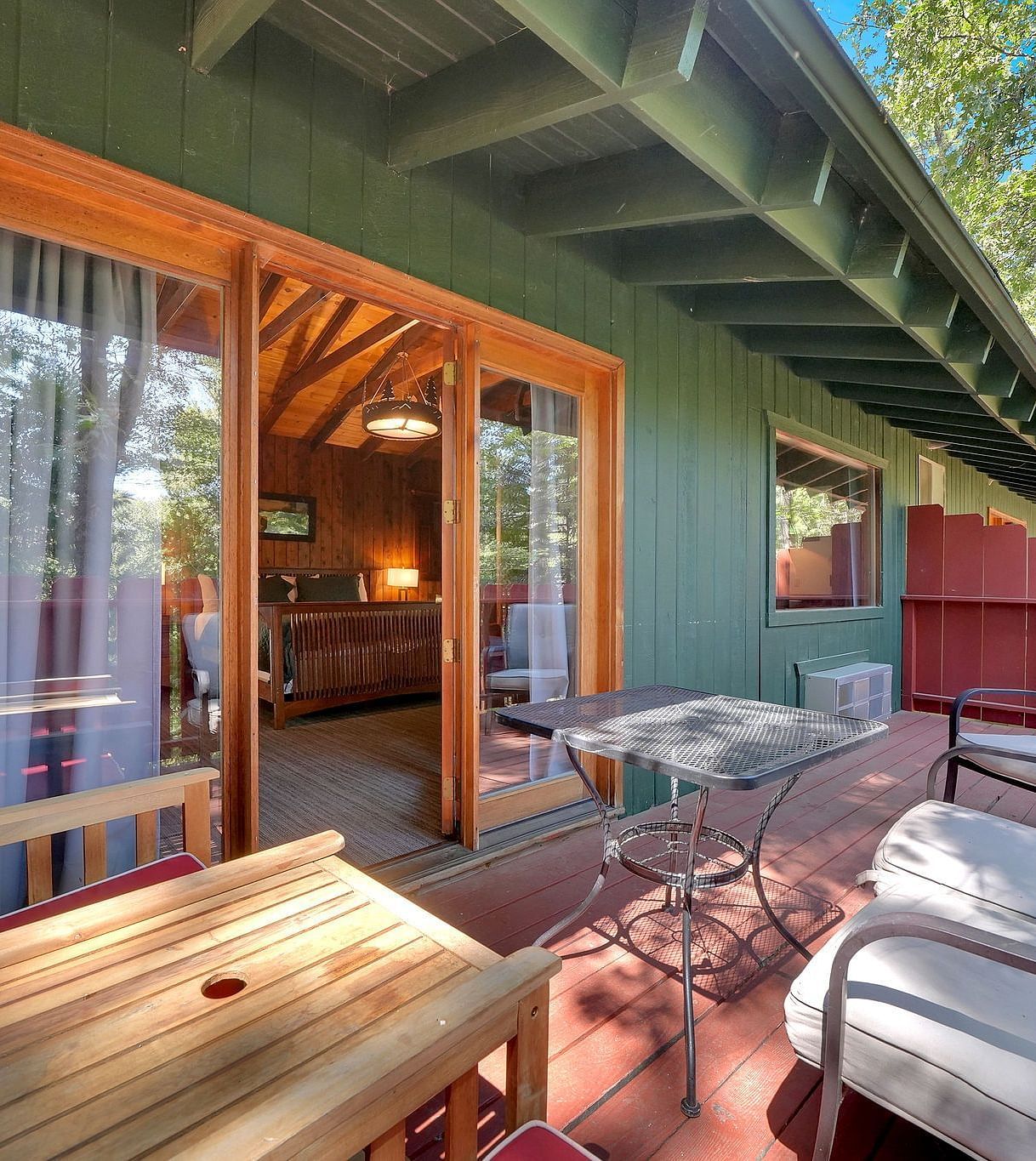 A view of the outdoor patio area o a cabin with sofa seating and a coffee table - Narrow Gauge Inn - A Serenite Hotel Near Fish Camp.