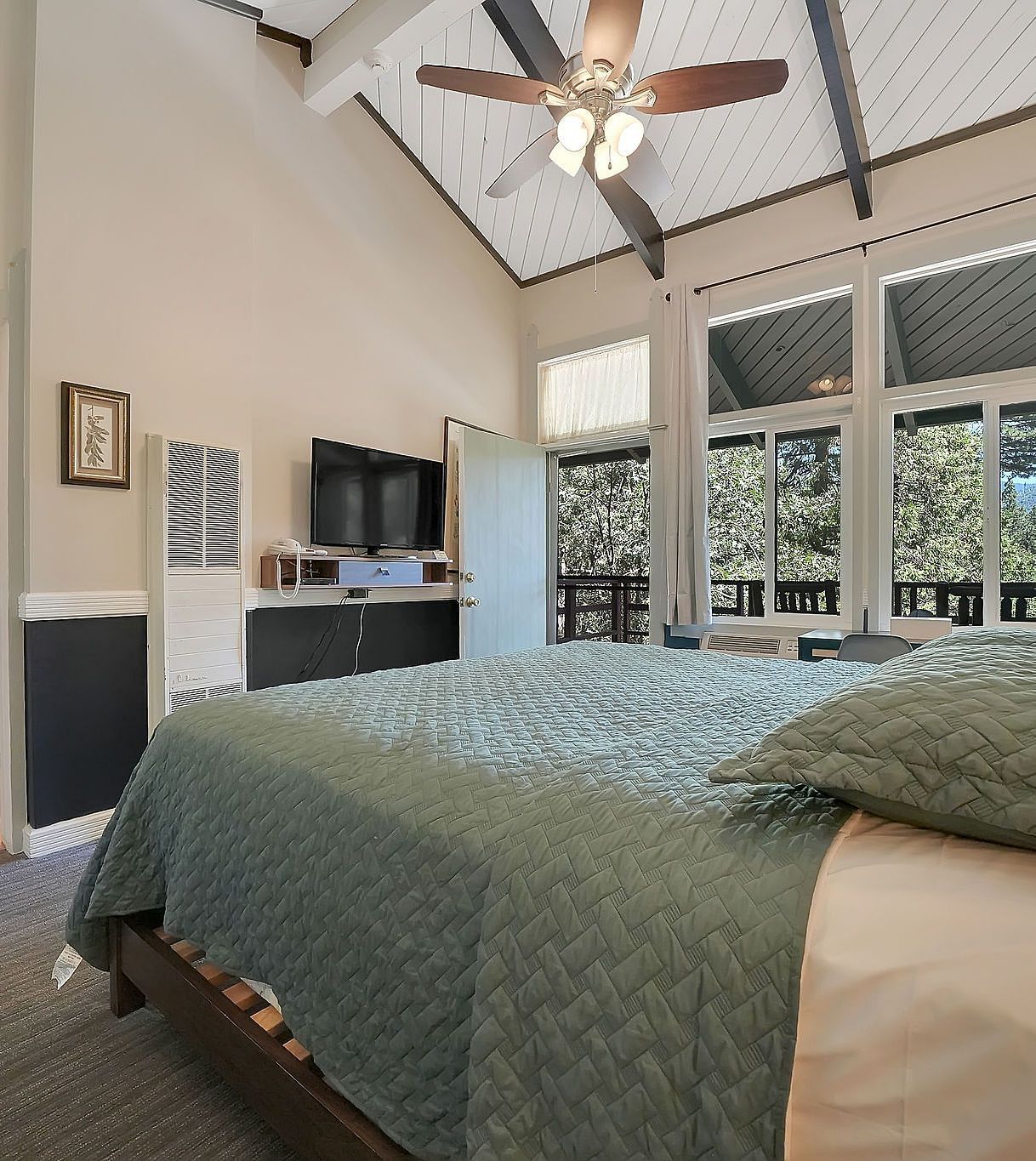 A view of a room at Narrow Gauge Inn with a double bed and sliding doors opening to a balcony.