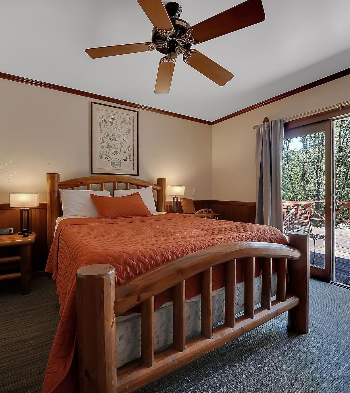 A view of a room at Narrow Gauge Inn with a double bed and sliding doors opening to a balcony.