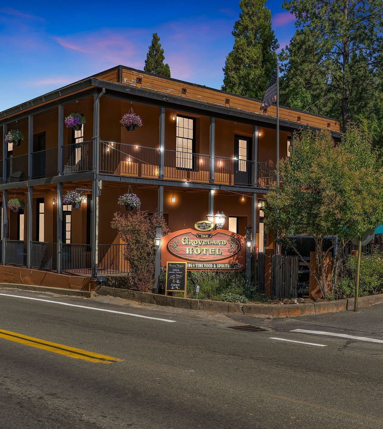 Facade of The Groveland Hotel with trees surrounding the building on a clear, blue day.