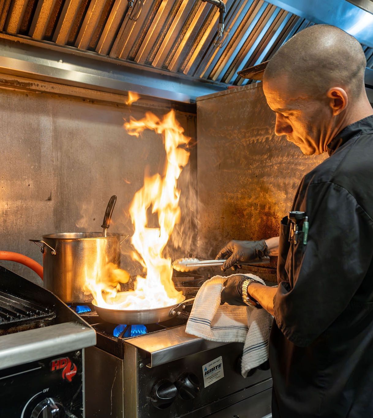 A chef cooking at the station in a commercial kitchen - The Groveland Hotel.