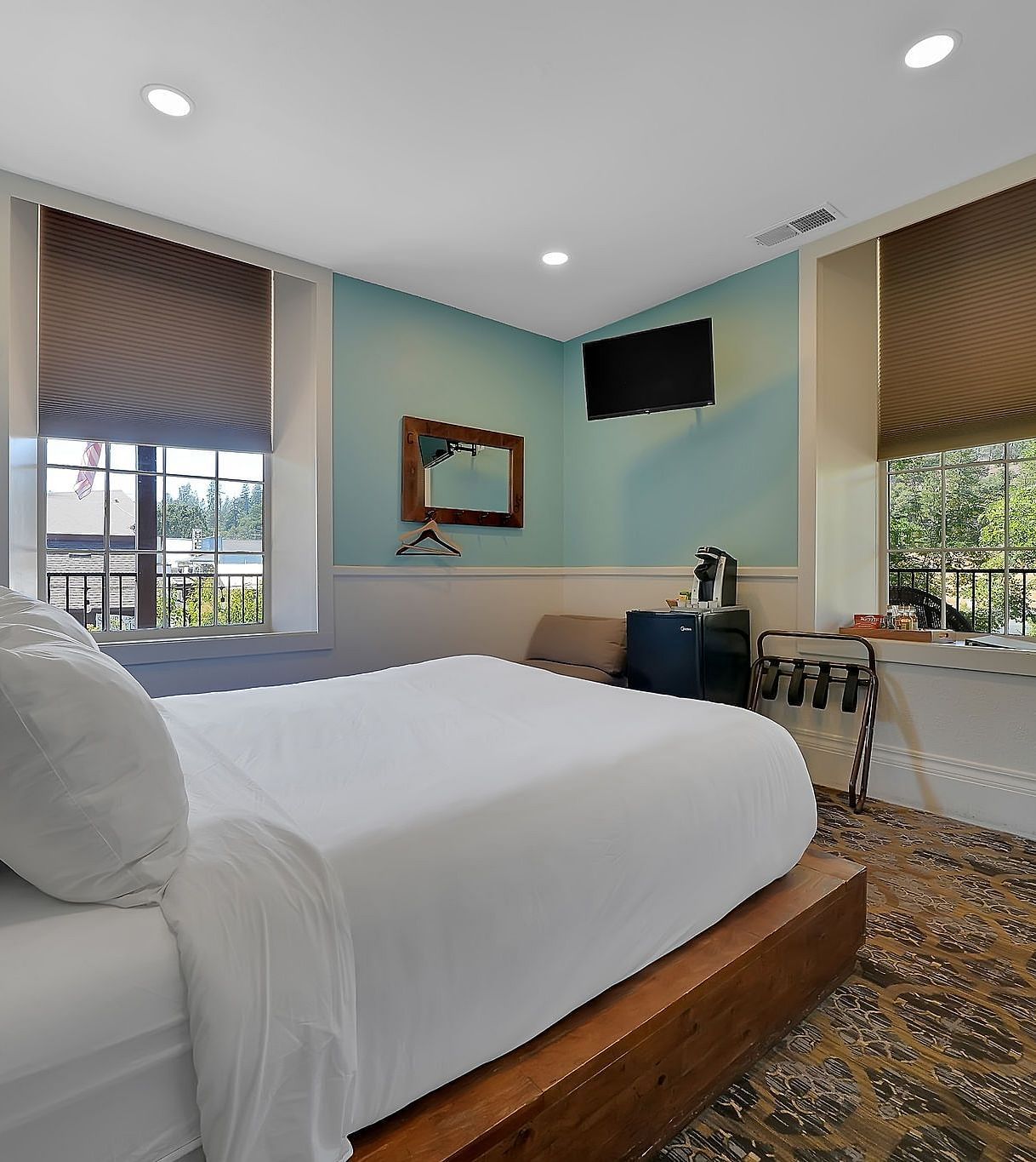 a room with a double bed and a television with light blue walls and a white ceiling - The Groveland Hotel.