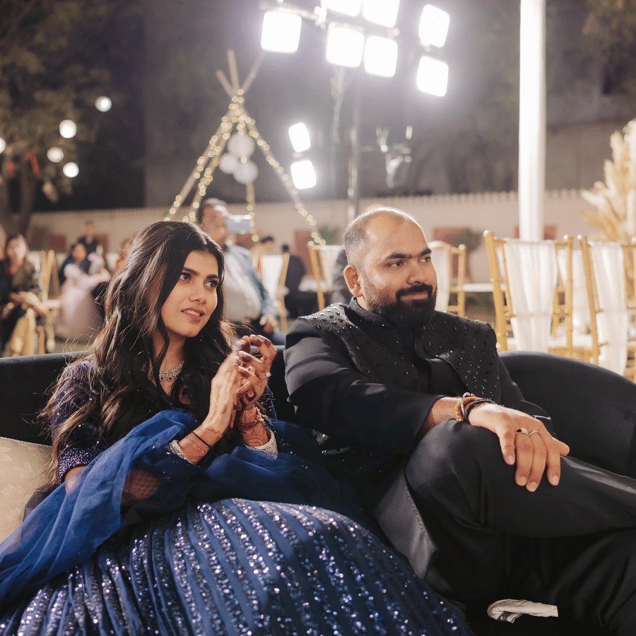 Couple enjoying a relaxed moment at an evening wedding event with ambient lighting.