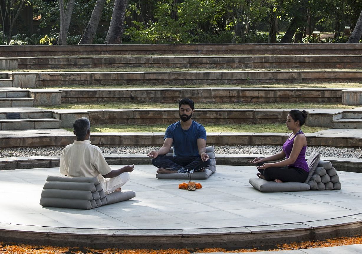 People sitting on a circular platform, outdoor setting, stone steps - Shreyas Retreat