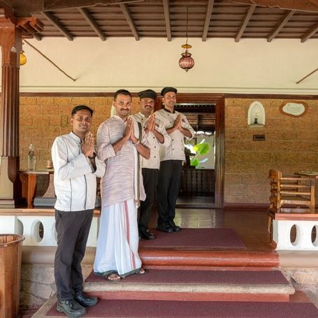 Evolve Back Coorg Hotel staff in traditional attire with hands folded