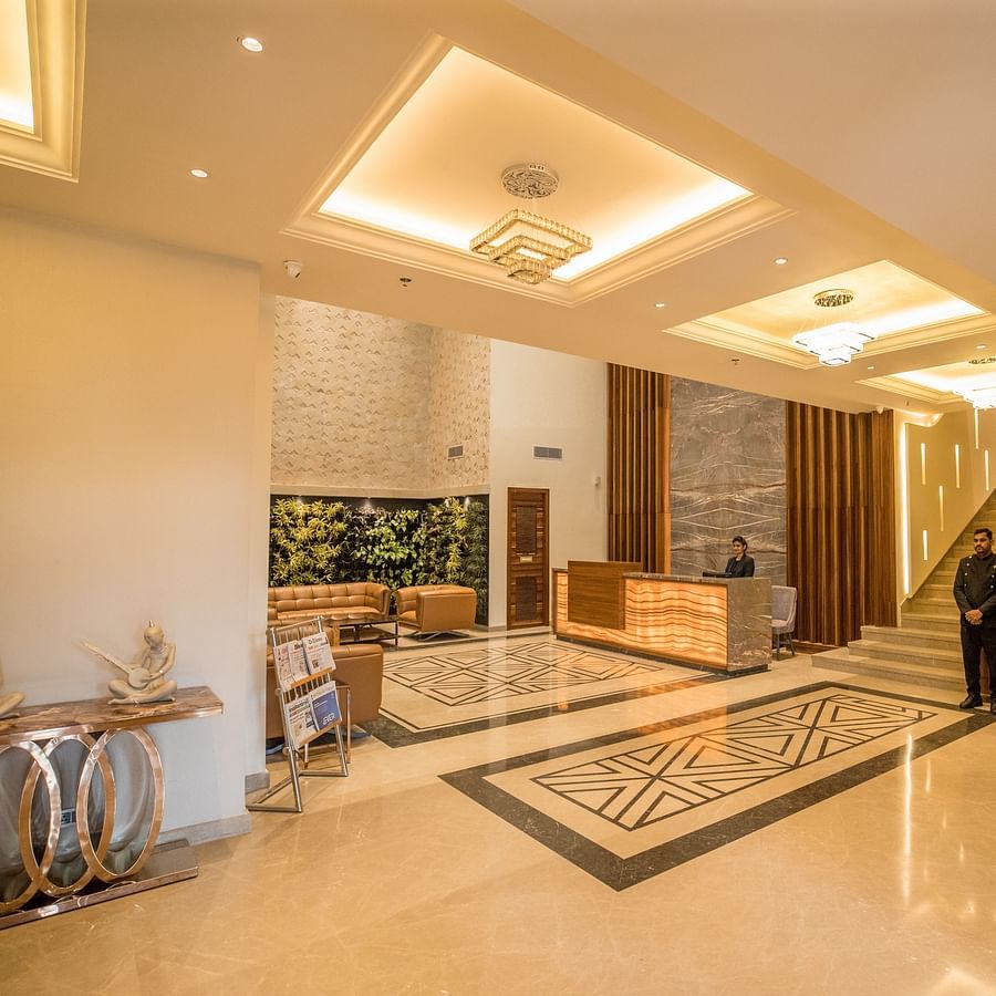 alt-text warmly lit interior of lobby at Ramada by Wyndham Kapurthala with a person standing in the reception area