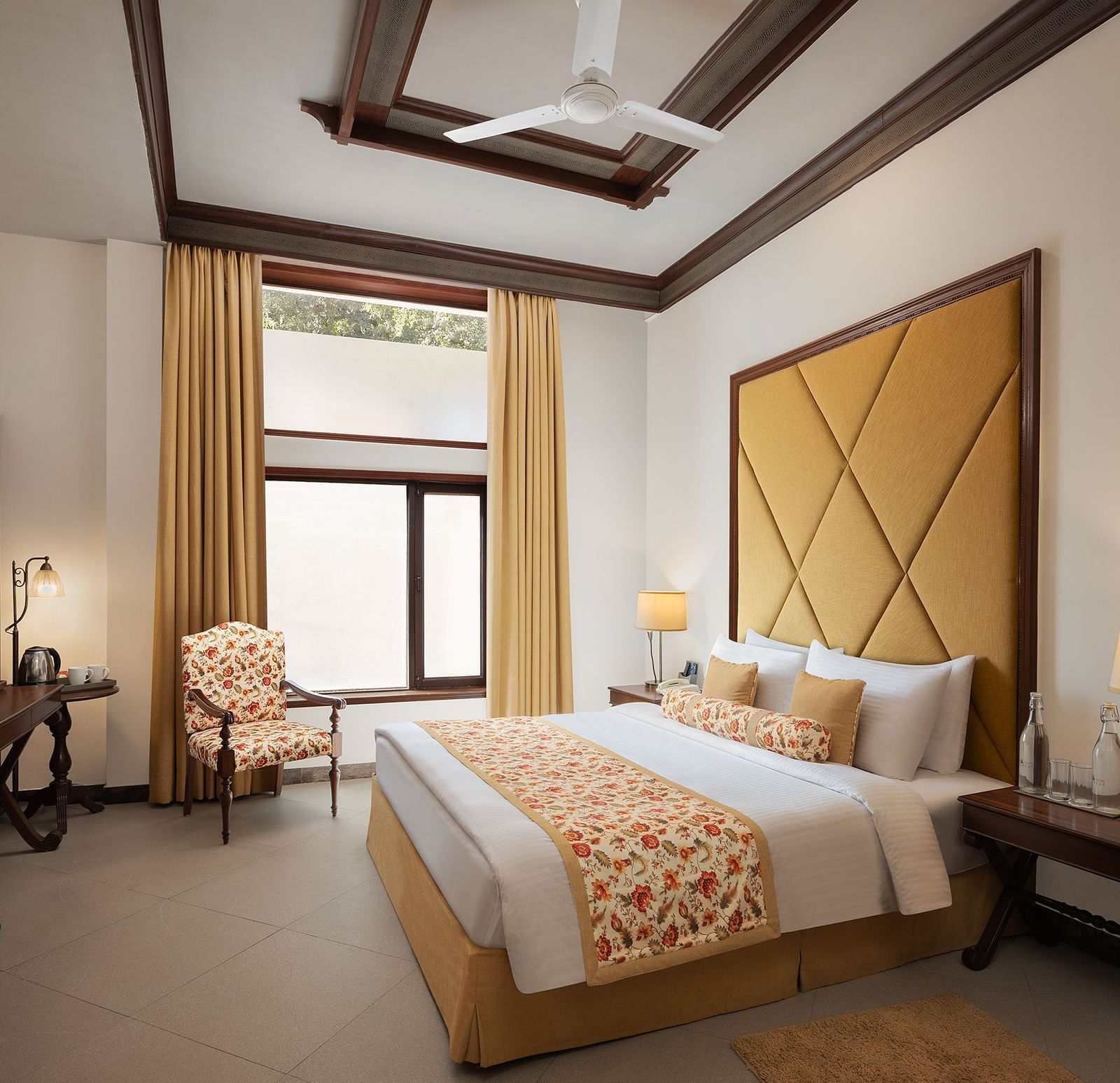 An image of a  cozy room in the naini retreat, nainital, with a double bed, wooden furniture, and a window. The room also features a ceiling fan, a TV .
