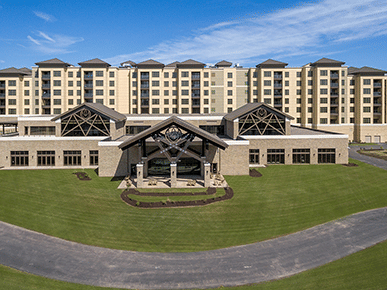 Exterior of YO1 Longevity & Health Resorts with a parking way running in front of it on a sunny day under blue sky .