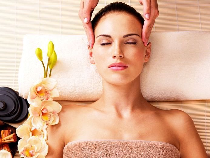 Woman relaxing during a spa treatment with flower petals and oils.