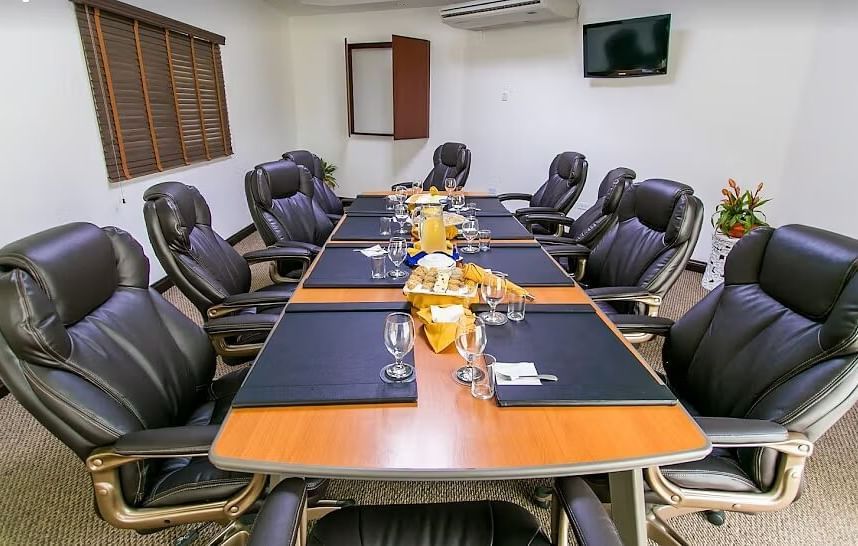 A conference room features a long, dark wood table surrounded by black office chairs | Board Room | Altamont Court, Jamaica