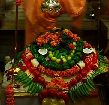 Garlands made of vegetables and flowers, with an oil lamp placed nearby in a temple setting