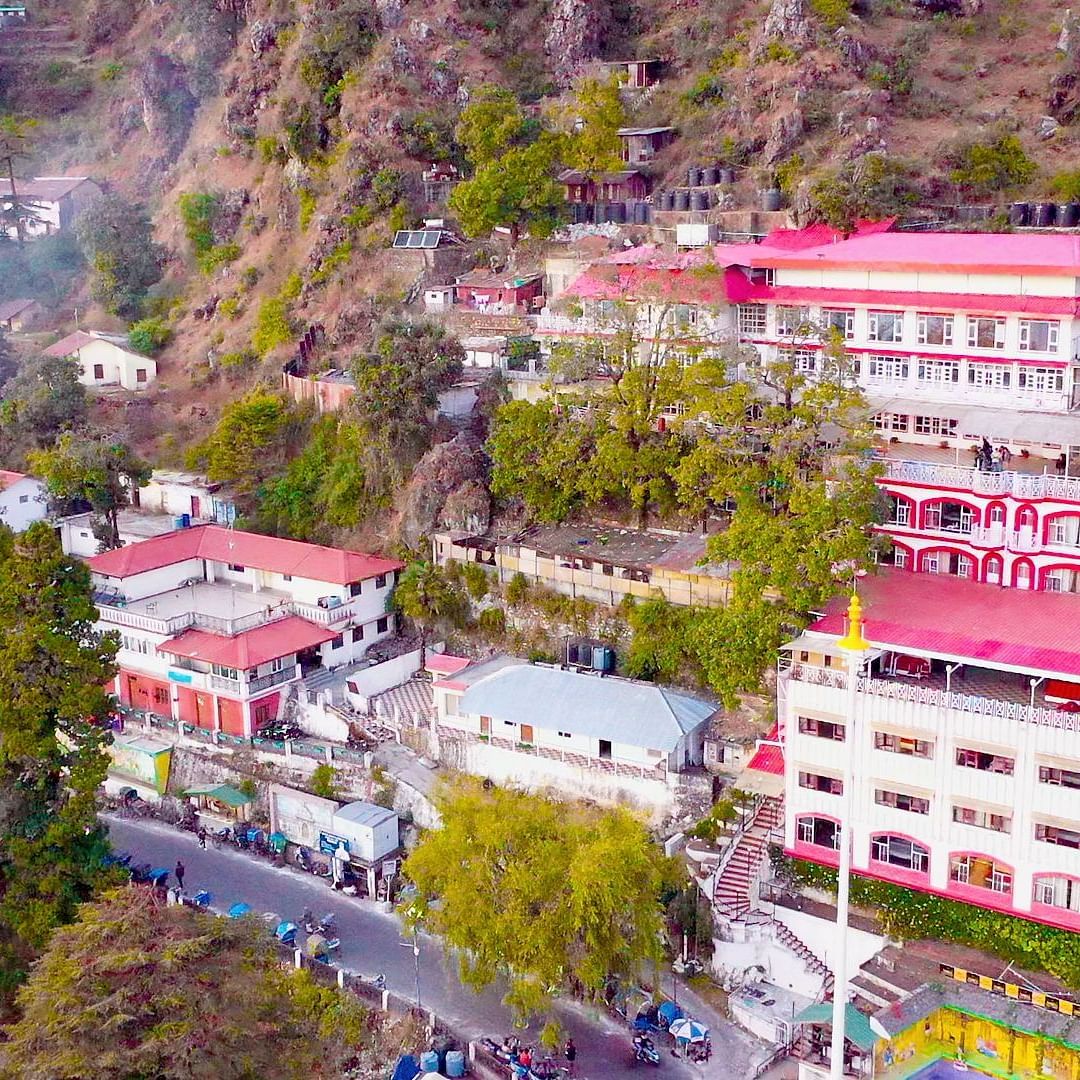 Aerial view of Mussoorie with buildings and trees around it.