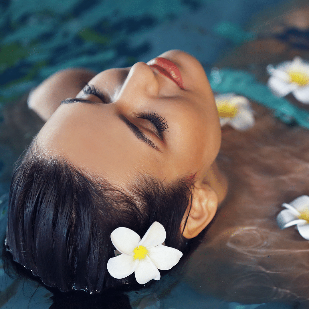 Woman floating serenely in water with flowers, capturing a moment of peacefulness