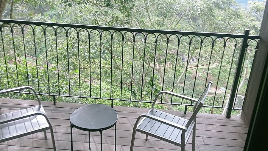 image of the balcony of the artist suite with lush green view from there with a coffee table and two chairs on the porch