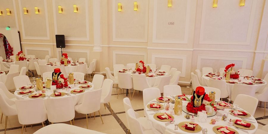A close-up of a decorated table at La Maison, Doha, with a focus on floral arrangements and place settings in a banquet hall.