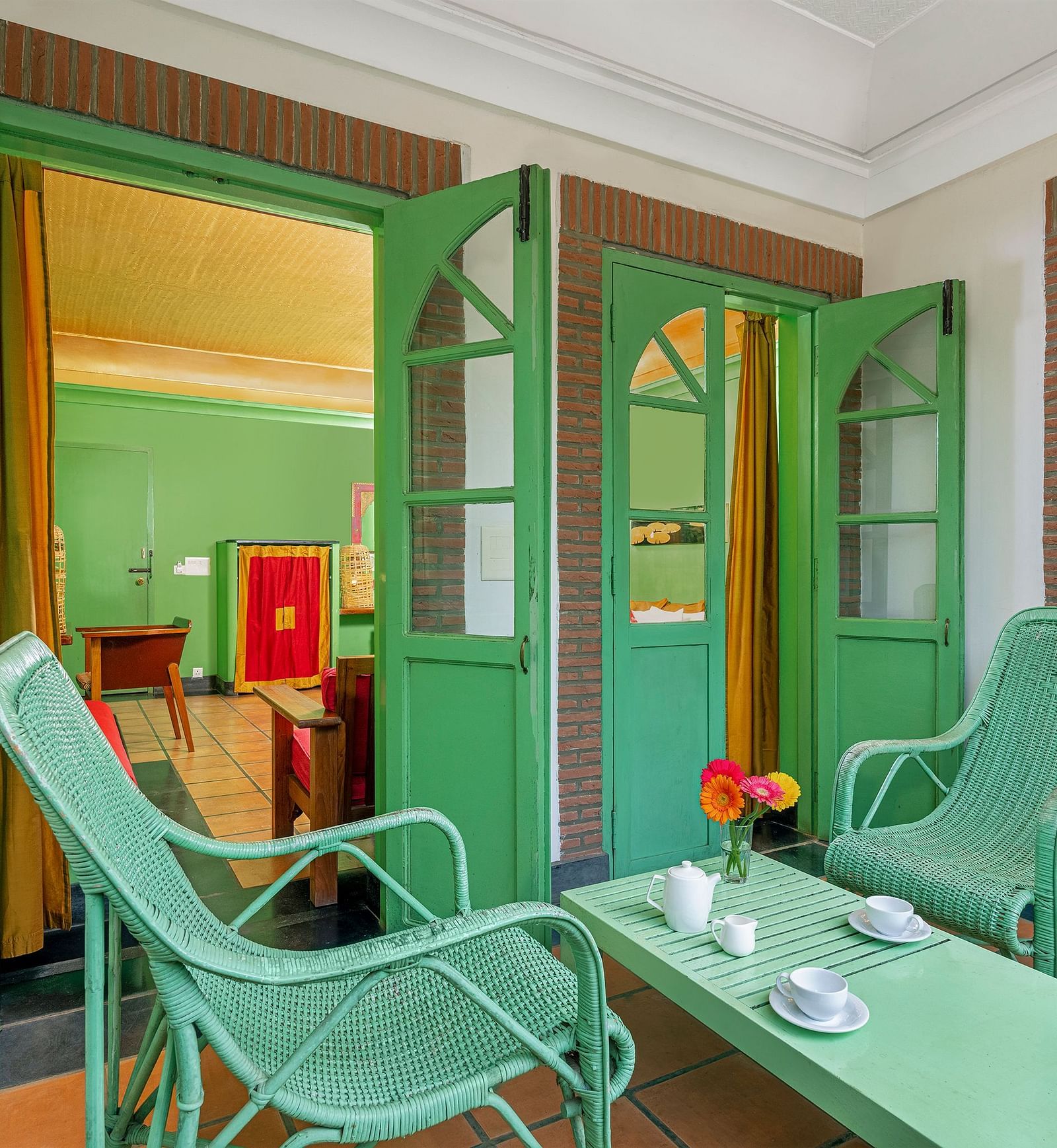 Two chairs and a coffee table with cups on them in the balcony of the suite | Mango Hill, Pondicherry