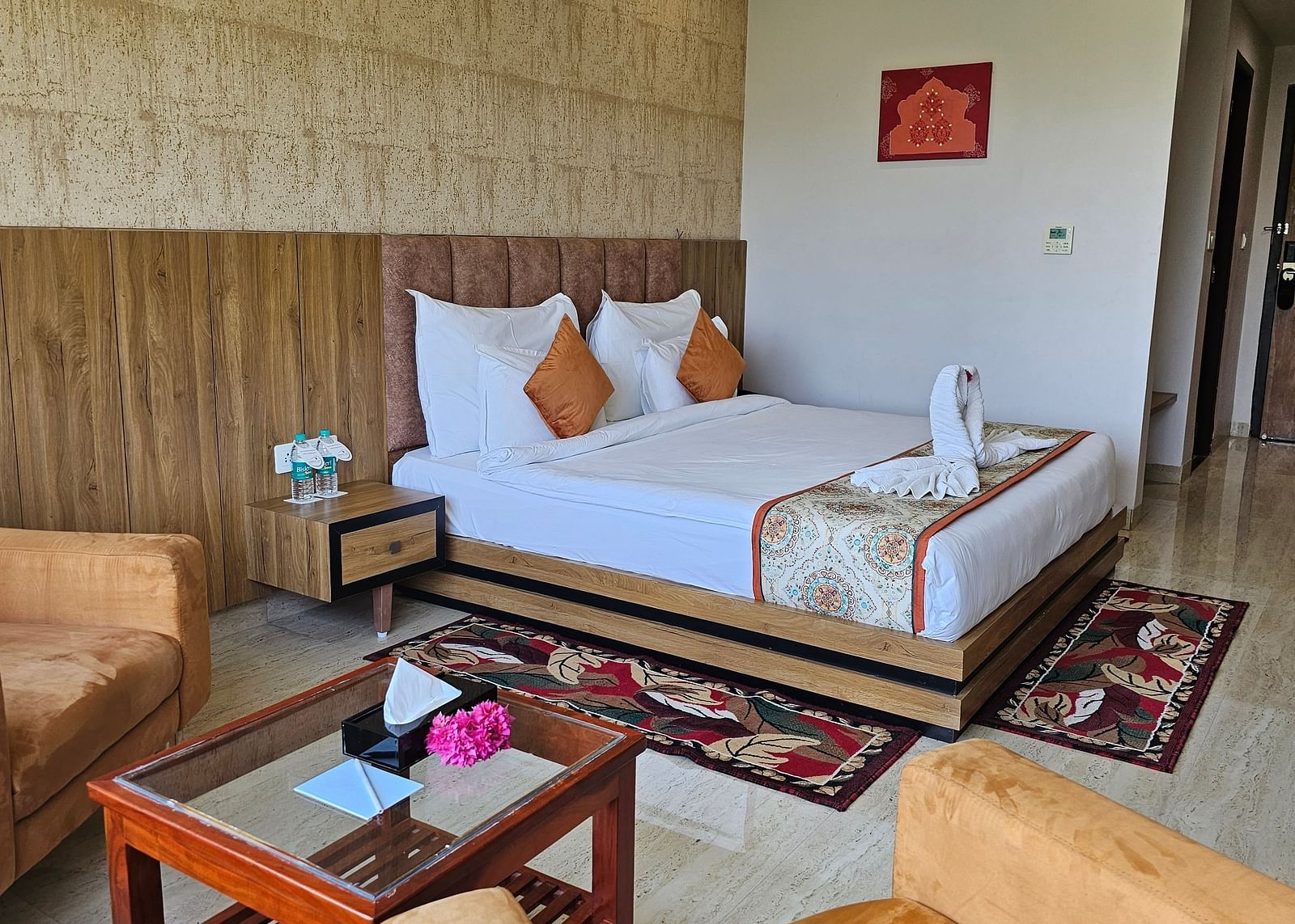 An interior shot of a hotel room at Bamboo Saa Mulberry Resort, with a bed, seating area, and a decorative rug.