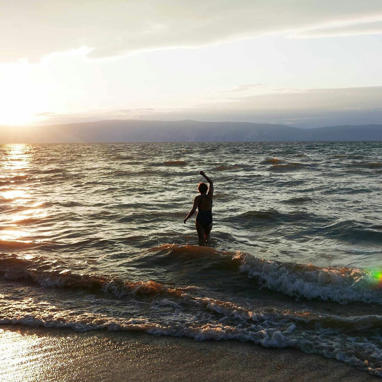 A photo of a person watching the sunset at the beach.
