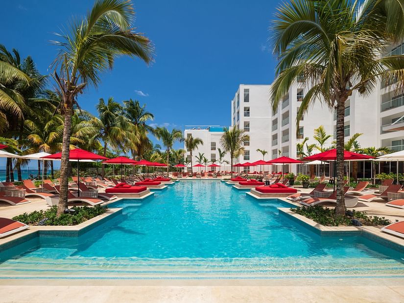 A wide-angle shot of a pool with red sun loungers on both sides - S Hotel Montego Bay, Jamaica