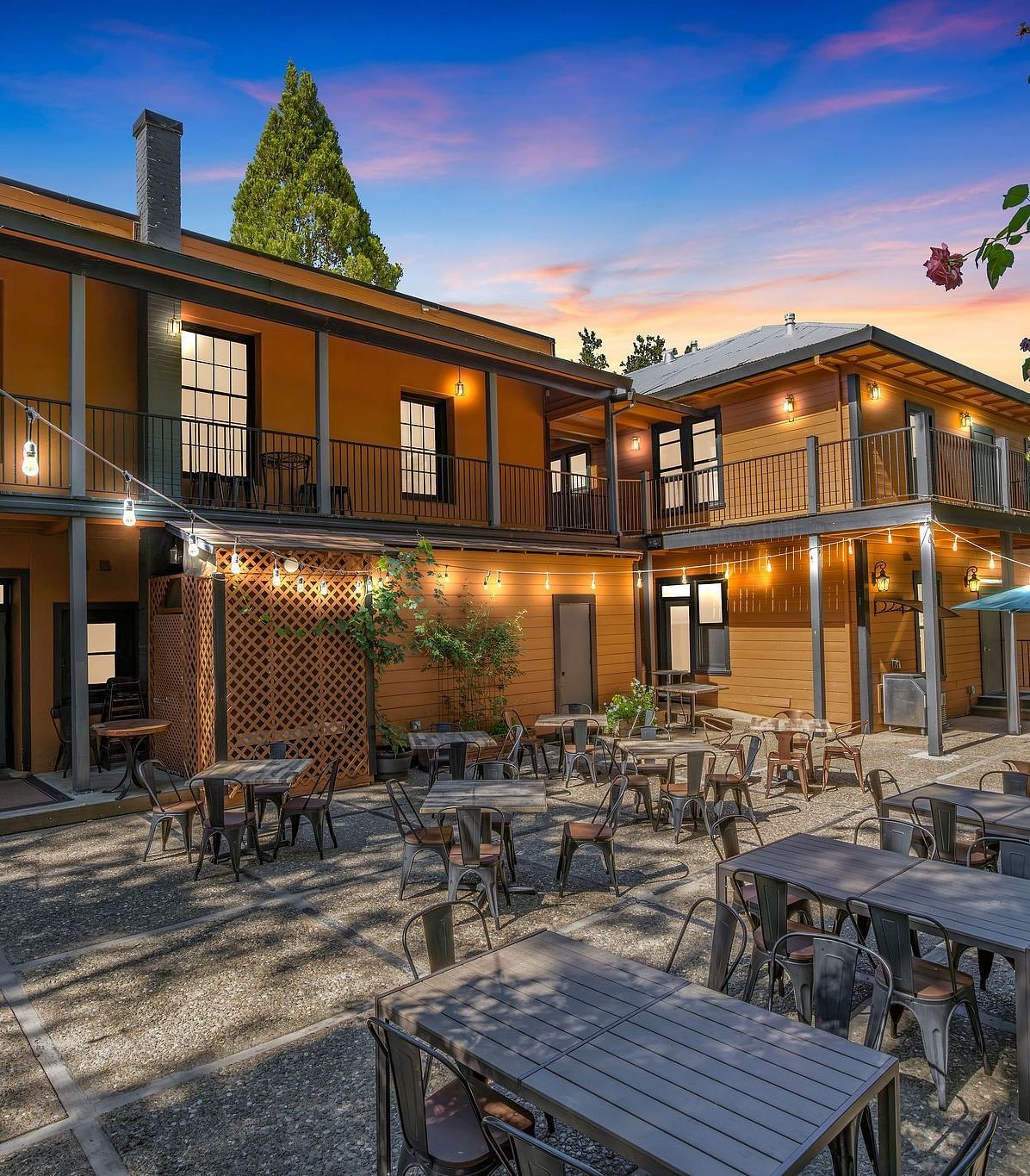 A view of the exterior of The Groveland Hotel with tables and chairs arranged in the backyard