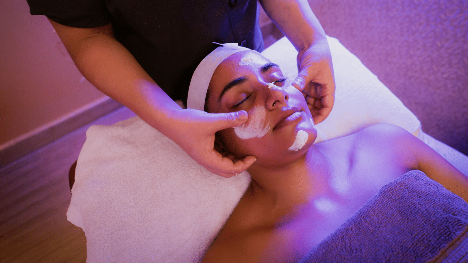 Therapist applying cream to a guest's face during a facial, with a white headband and towels in place, at Hasta Spa, Ilara Hotels & Spa, Tada.