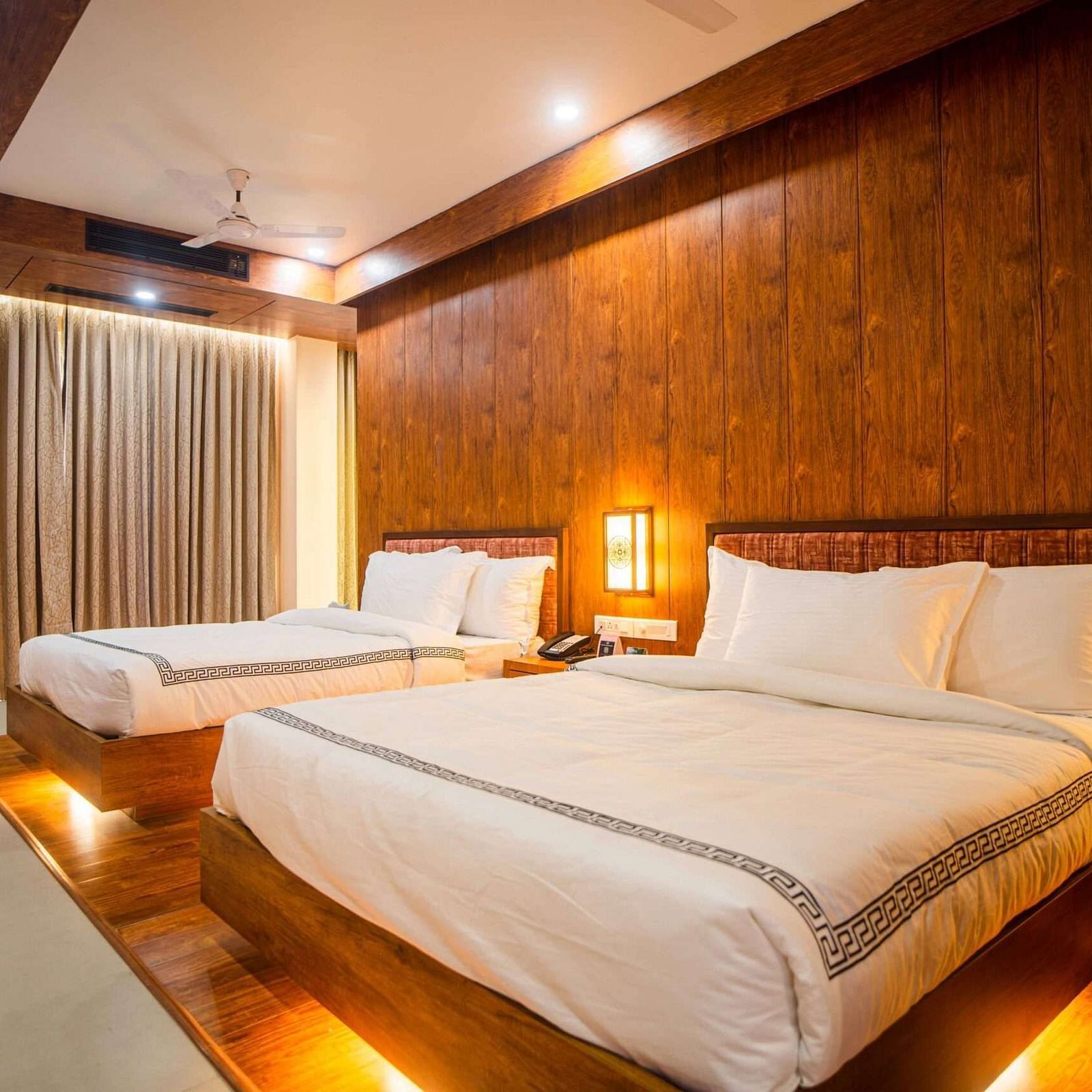 The comfortable rooms at Mansha Palace offer two beds, warm wooden accents, and a strategically placed opening that provides a peek into the bathroom.
