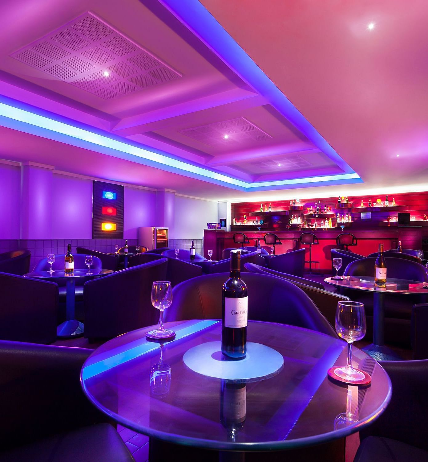 An image of a bar with illuminated purple lights at Regency Madurai by GRT Hotels
